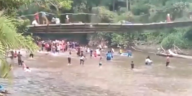 A bridge with people starts to collapse above people in the water in Indonesia